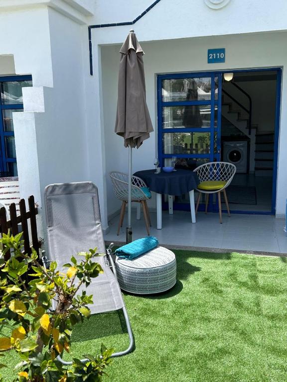 a patio with a chair and an umbrella and a table at Pool Front Playmar Maspalomas in San Bartolomé