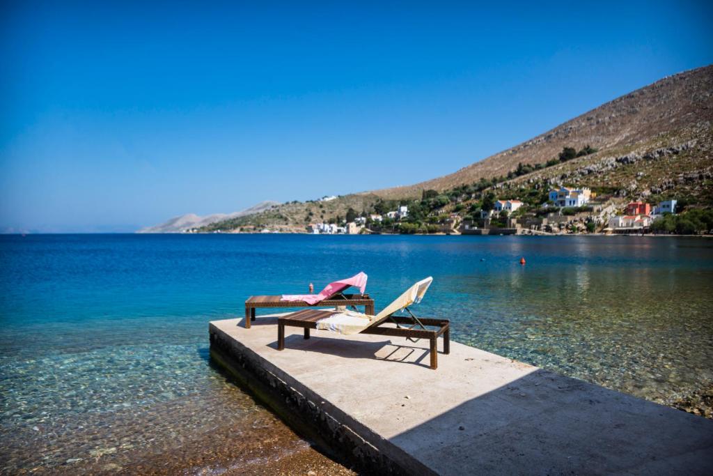 dwa krzesła siedzące na przystani obok jeziora w obiekcie Villa See the Sea w mieście Simi