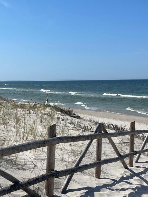 a wooden fence on the beach near the ocean at Prawdziwe Morze in Sasino