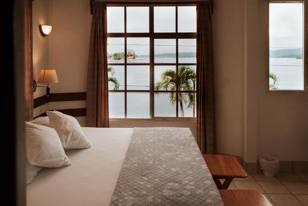 ein Schlafzimmer mit einem Bett und einem großen Fenster in der Unterkunft Hotel Casa Amelia in Flores