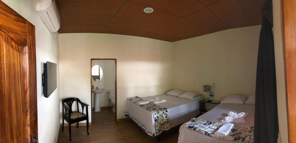 1 dormitorio con 2 camas, silla y espejo en Hostal DEYLUWIN en Juayúa