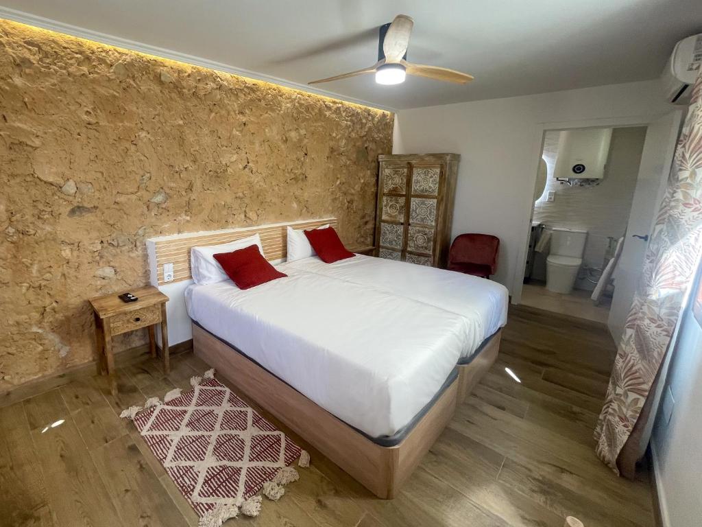 sypialnia z łóżkiem z białą pościelą i czerwonymi poduszkami w obiekcie Estancia dos Olivos w mieście Quesa