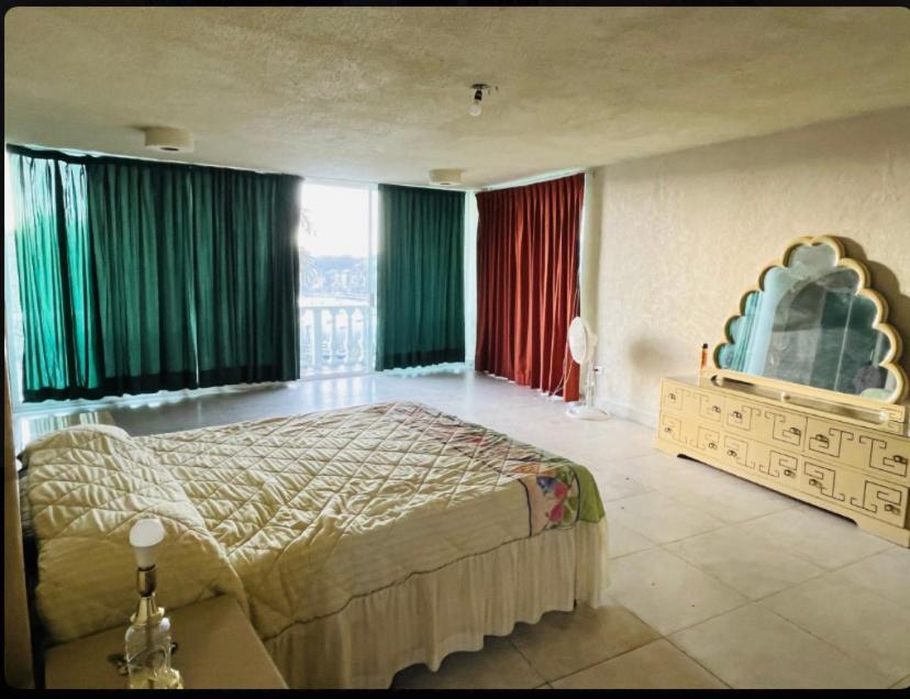 - une chambre avec un grand lit et des rideaux verts dans l'établissement Casa con vista espectacular al mar con alberca, à Acapulco