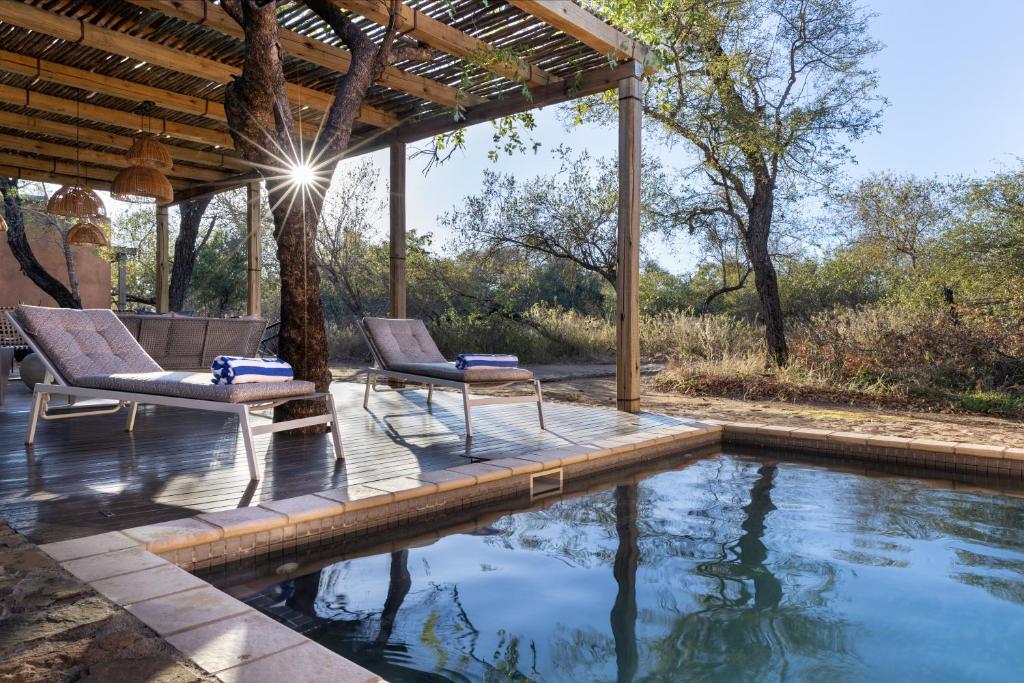 a patio with two chairs and a swimming pool at Rixile Kruger Lodge in Skukuza