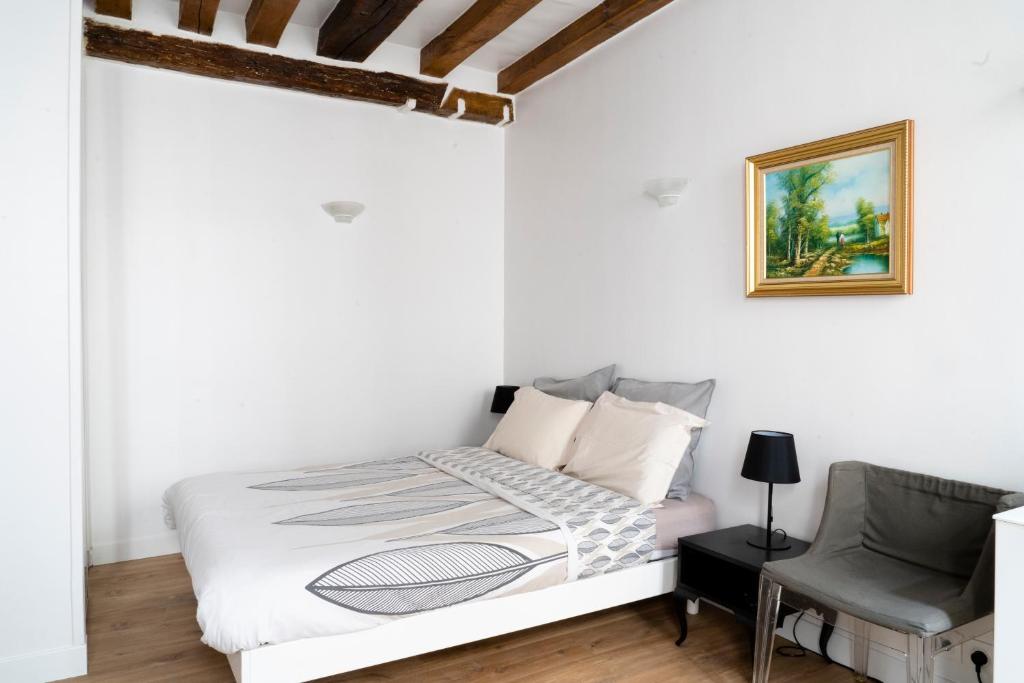 une chambre blanche avec un lit et une chaise dans l'établissement Le 64 Rue Chapon, à Paris