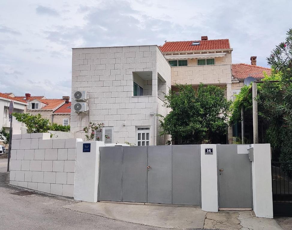 uma casa branca com uma cerca em frente a um edifício em AVA Studio apartment and Room em Dubrovnik