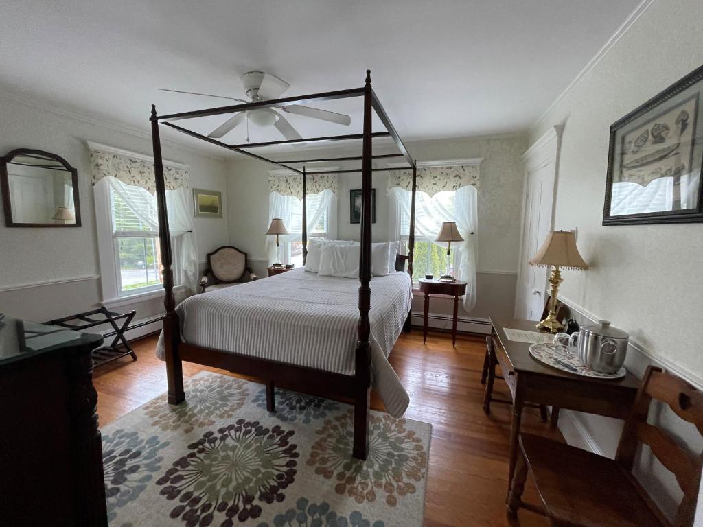 ein Schlafzimmer mit einem Himmelbett und einem Tisch in der Unterkunft Bourne Bed and Breakfast in Ogunquit