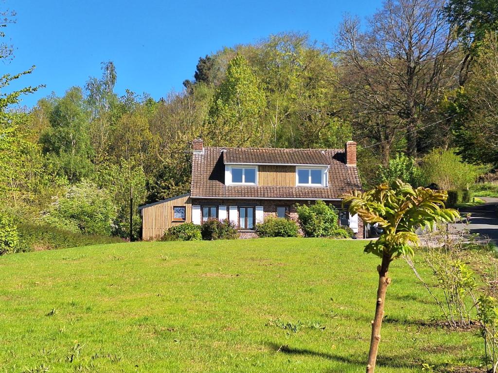 une maison sur un champ herbeux avec un arbre dans l'établissement La maison de Carine et Didier, à Godewaersvelde
