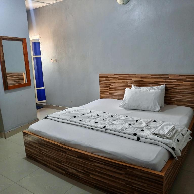 Schlafzimmer mit einem großen Bett mit einem Kopfteil aus Holz in der Unterkunft Hotel De Pisces in Uyo