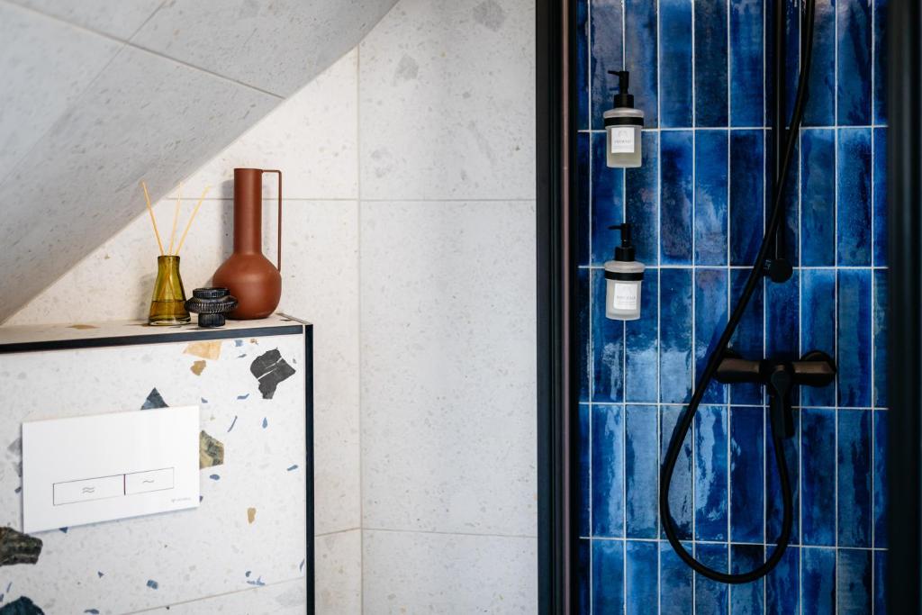 a bathroom with a shower with blue tiles at Nook with a view - Quelle in Győr