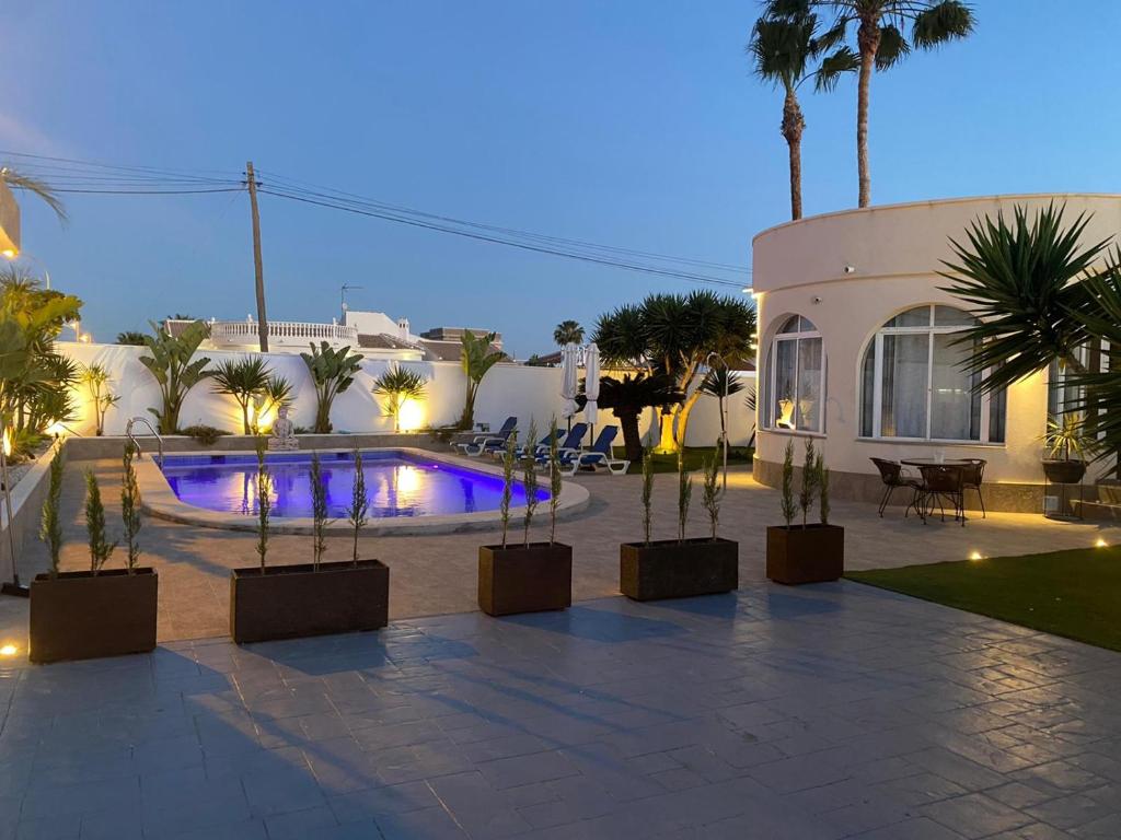 un patio con una piscina con palmeras y un edificio en Detached Villa With Private Pool Torrevieja, en Torrevieja