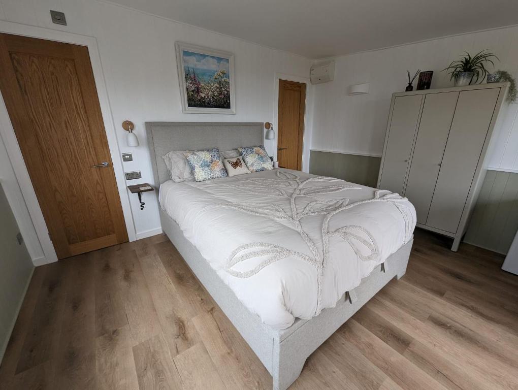 a bedroom with a large bed and a wooden floor at Cotts Cabin - Welcombe - 2 min walk to pub in Bideford