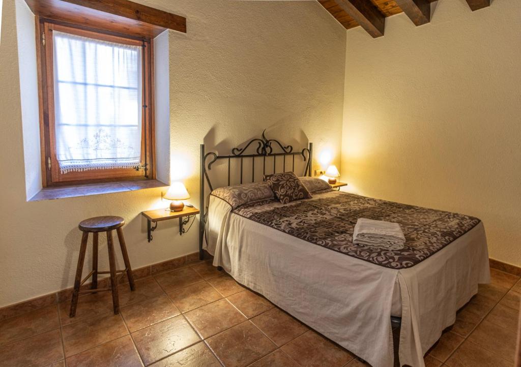 een slaapkamer met een bed, een raam en een kruk bij Can Tubau - Casa rural - Apartaments in Campelles