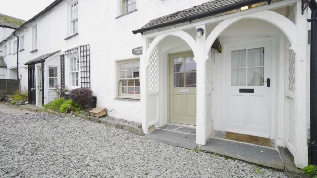 a white house with a green door on a street at Gingerbread Cottage in Hawkshead
