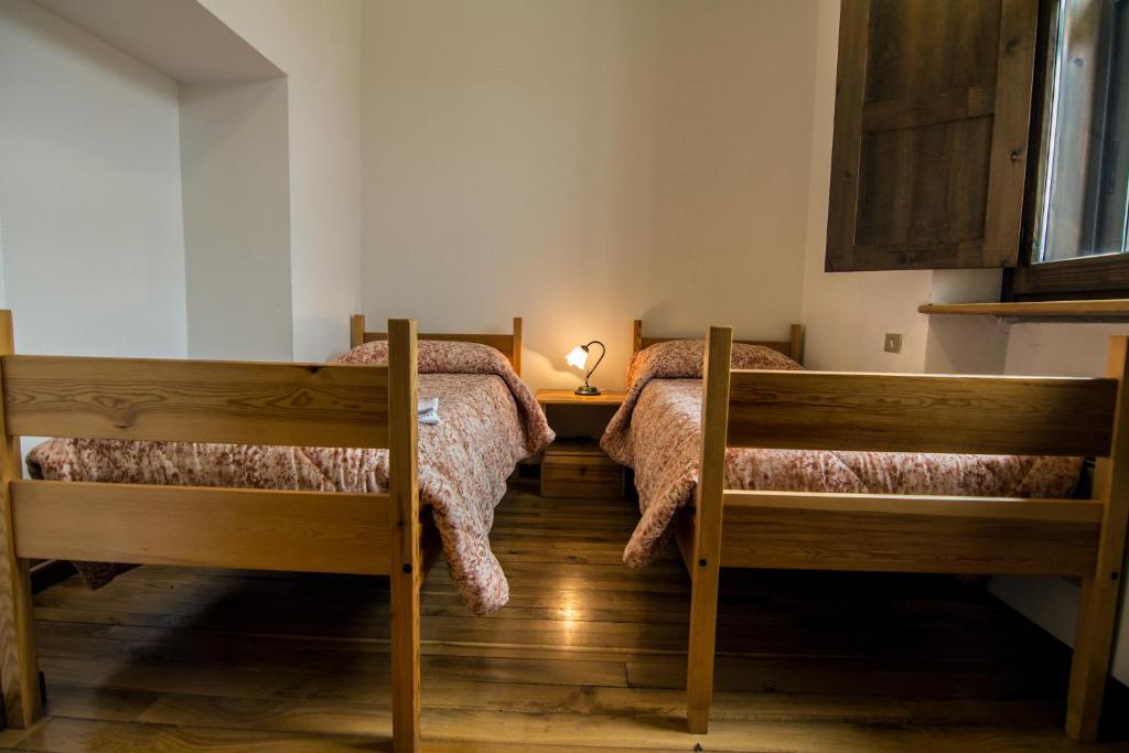 a bedroom with two beds and a lamp on a table at Il Camoscio Mountain & Bike in Rovere