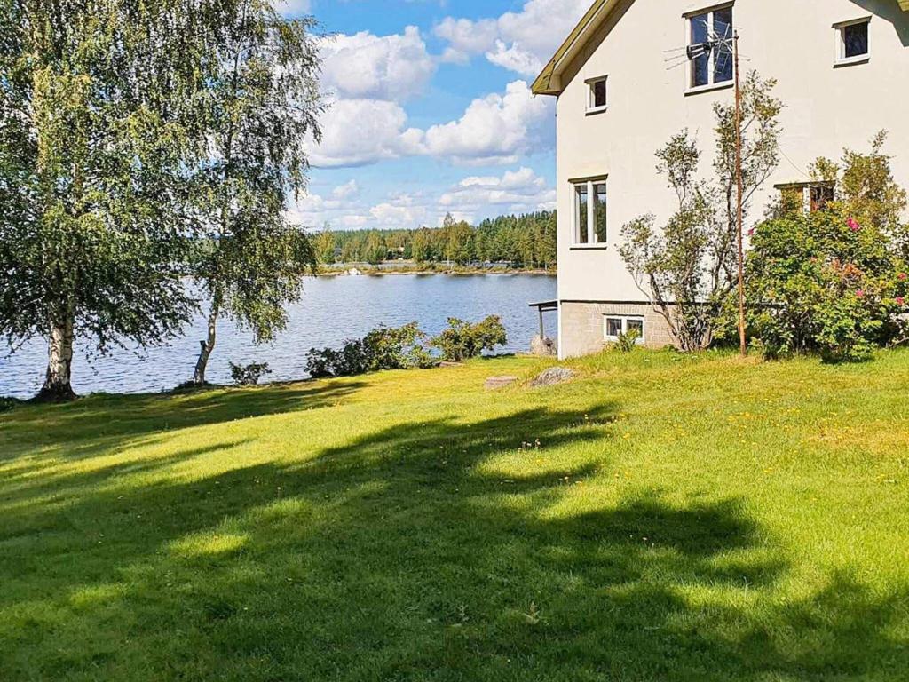 a large house on a lawn next to a lake at Holiday home VIKSJÖFORS in Viksjöfors
