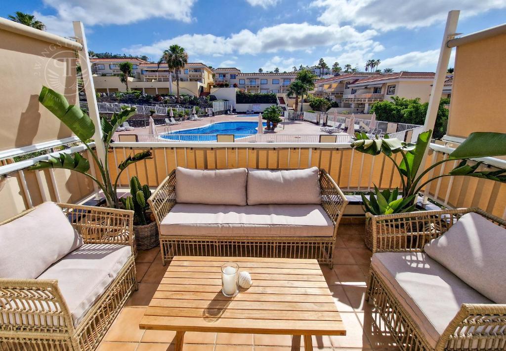 a patio with wicker furniture and a swimming pool at 2 Wings Tenerife - Apartment Chayofa in Chayofa