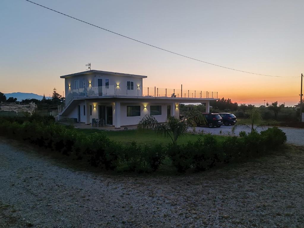 una casa blanca con una puesta de sol en el fondo en Cà del Re Holiday, en Partinico