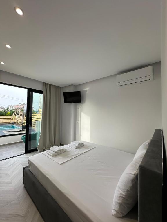 a white bed in a room with a large window at Noa Boutique Hotel in Ksamil