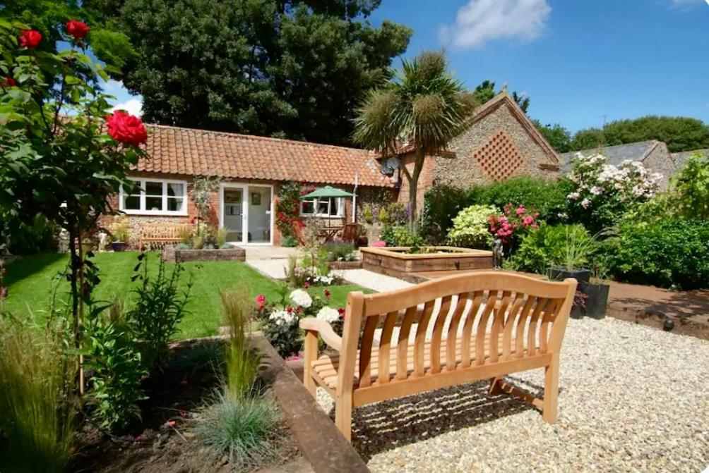 a wooden bench in the garden of a house at Coastal Hidden Gem - Twin en-suite room with garden in Wells next the Sea