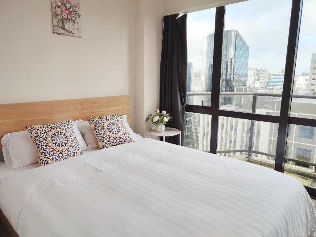 a bedroom with a white bed and a large window at City Garden Penthouse in Auckland