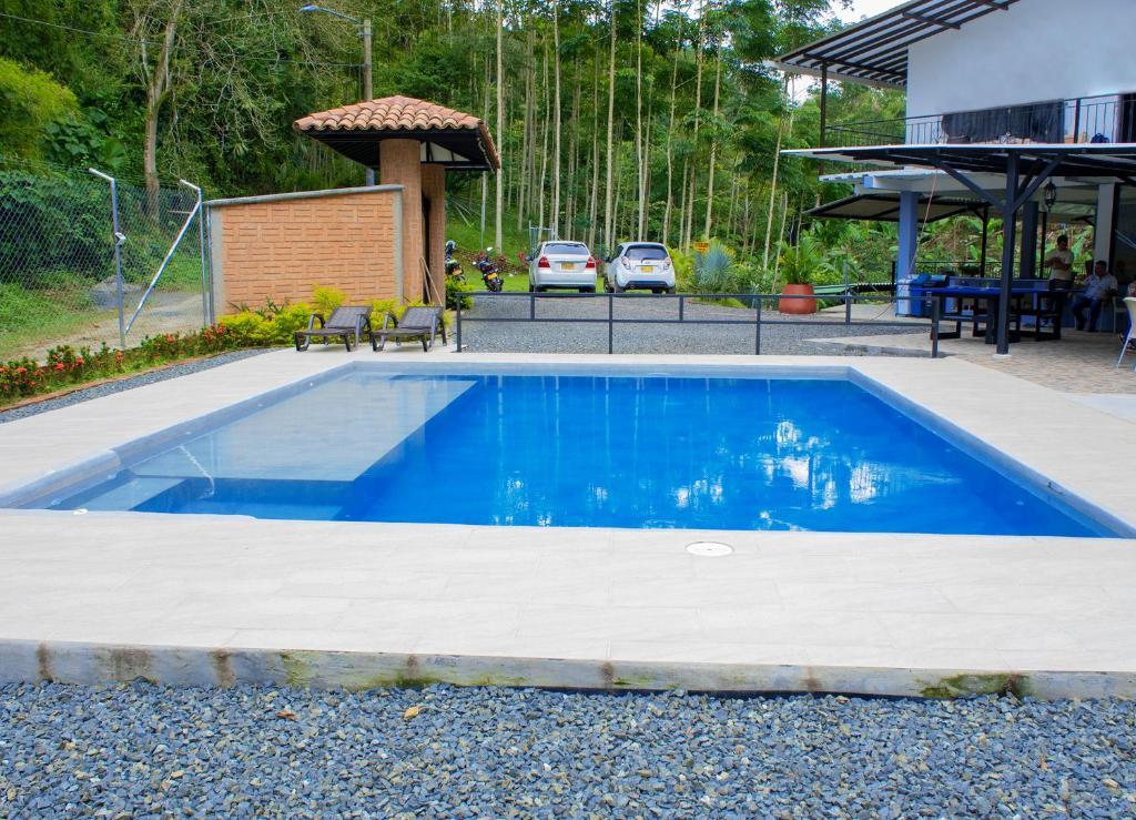 a blue swimming pool in a yard next to a house at FINCA CAMPESTRE EL PORVENIR in Quimbaya