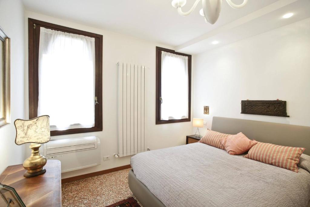 a bedroom with a bed and a desk and two windows at Cà Del Fotografo in Venice