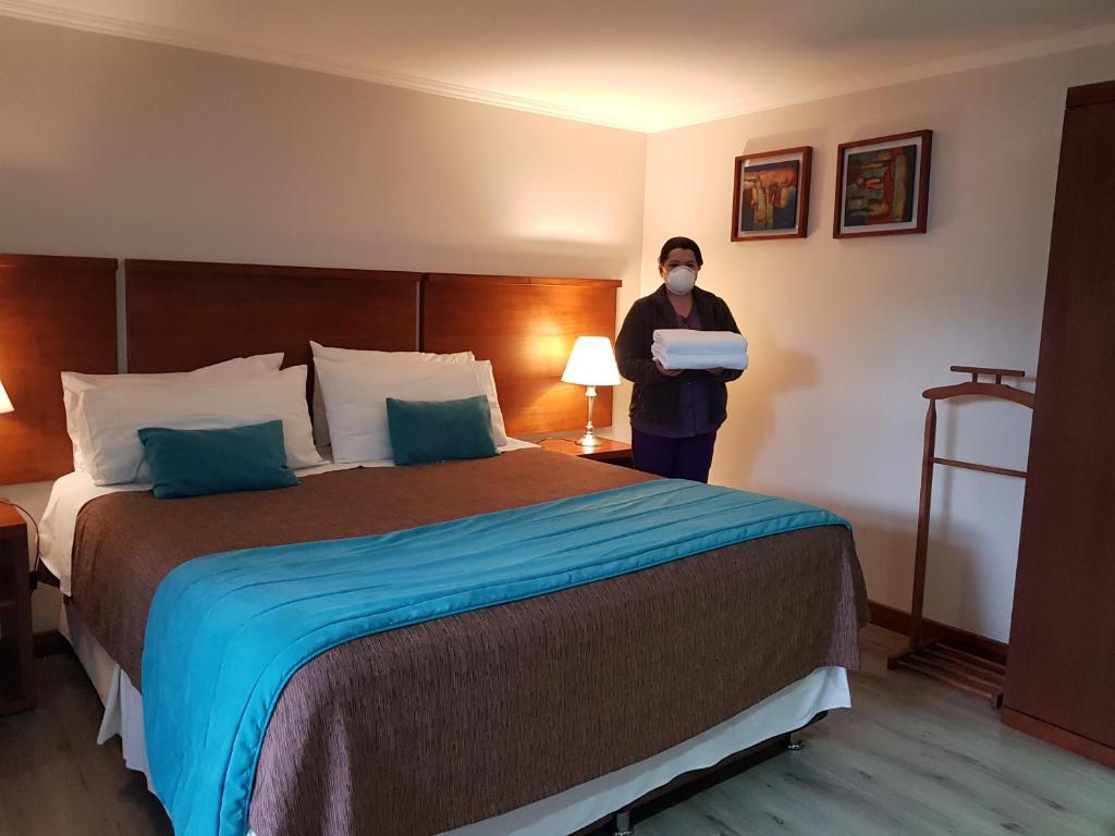 a person wearing a mask standing next to a bed at Hotel D&V Concepción in Concepción