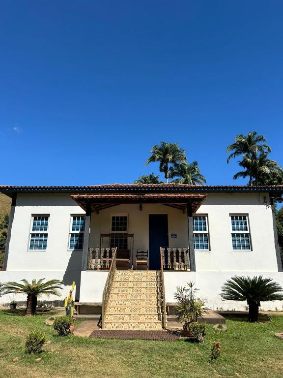 a white house with palm trees in the background at Hotel Fazenda Palmeiras in Rio Casca
