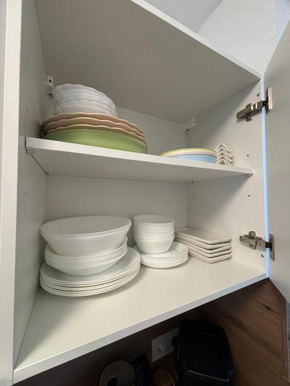 un armario blanco lleno de platos y tazones en Nisay Home - City House - Central Location en Ludwigsburg