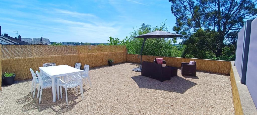 un patio con mesa, sillas y sombrilla en La campagne à la ville, en Sablé-sur-Sarthe