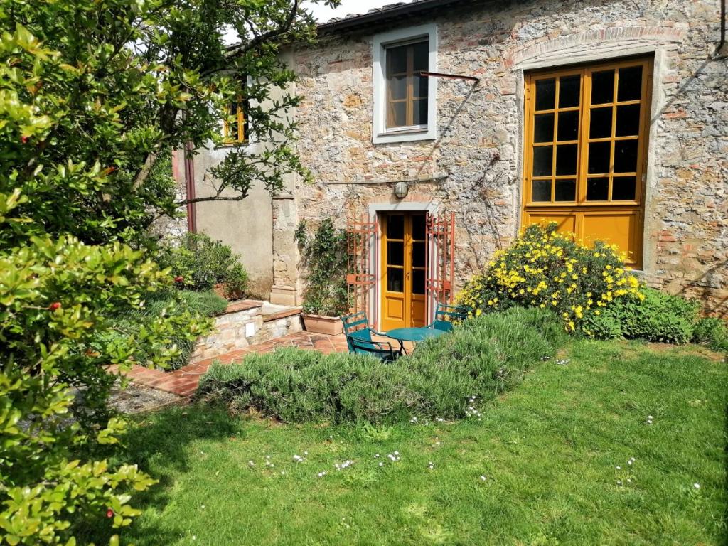 uma casa de pedra com uma porta amarela e um quintal em Residenza le Api em Lucca