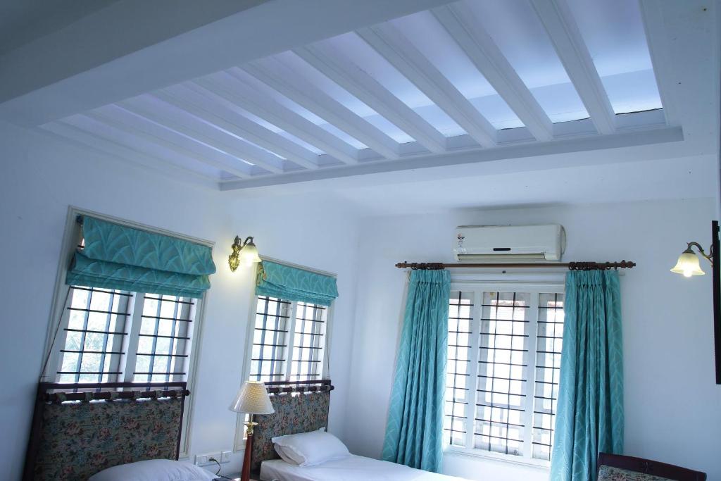 1 dormitorio con 2 ventanas con cortinas verdes en Fortbeach Service Apartments, en Kochi