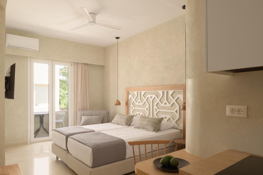 a white bedroom with a bed and a table at Apollo Plakias in Plakias