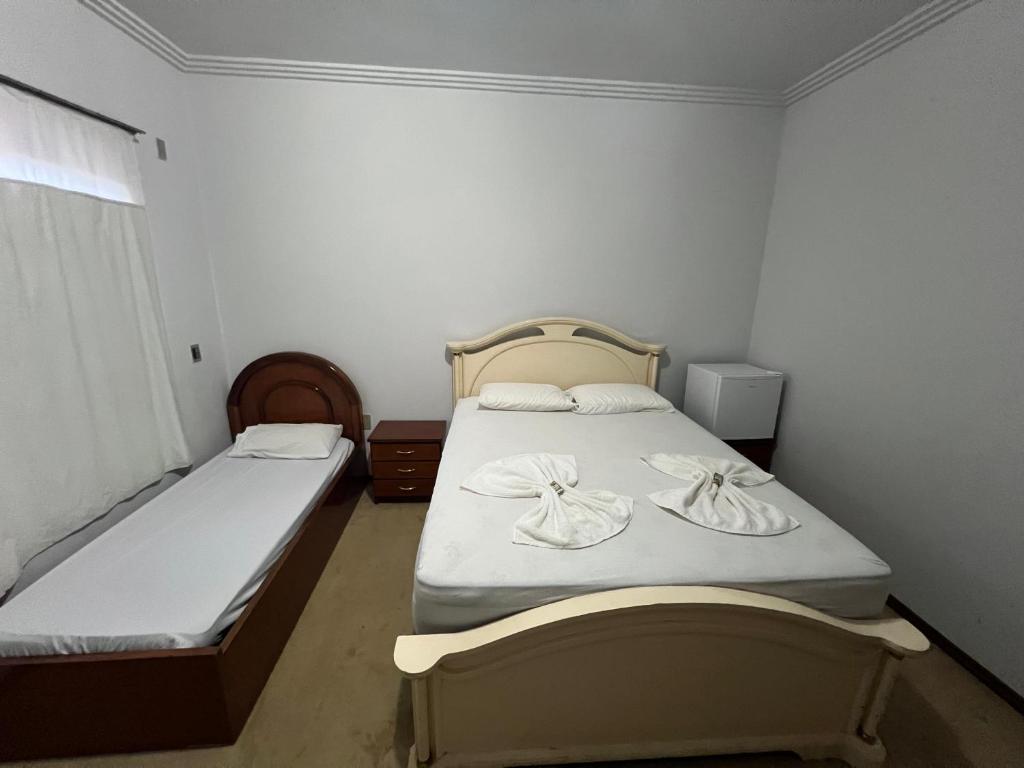 a small room with two beds and a window at Suíte no centro com 2 camas e hidromassagem in Sinop