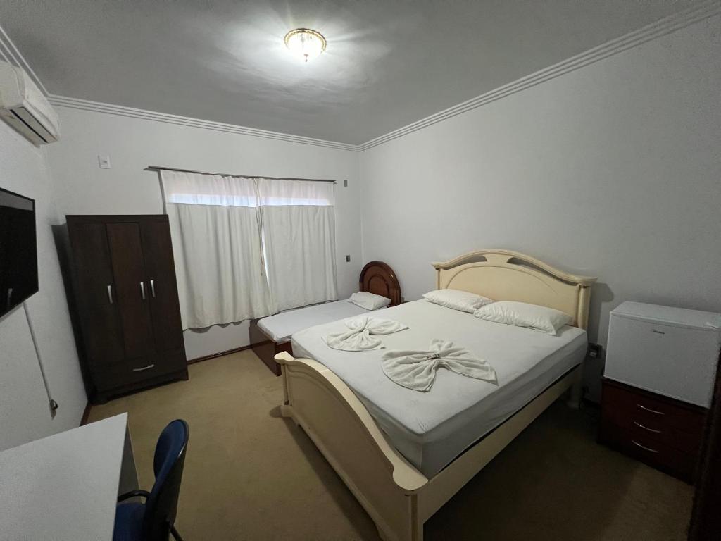 锡诺普Quarto no centro com 2 camas e hidromassagem的一间卧室配有一张床、一个梳妆台和一扇窗户。
