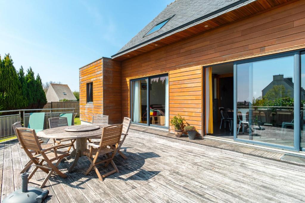 un patio de madera con una mesa y sillas en una terraza en Cocon vert proche mer, en Plouhinec