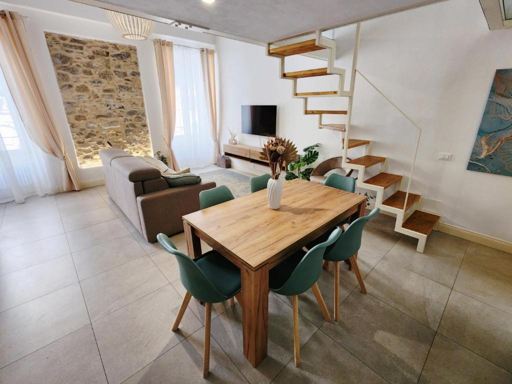 sala de estar con mesa de madera y sillas verdes en CLASSY HOMES - Acquamarina en Sanremo
