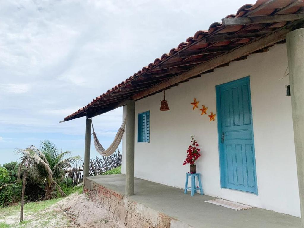 ein Haus mit einer blauen Tür und einer Blumenvase in der Unterkunft Casinha Estrela do Mar o Oceano aos seus Pés in Aracati