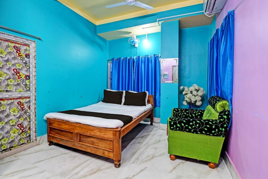 OYO Mohona Residency & Restaurant في Nimtita: غرفة نوم بجدران زرقاء وسرير وكرسي