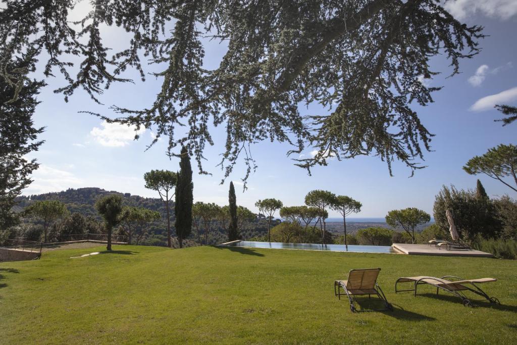 a park with two chairs and a swimming pool at Podere Il Castellaccio in Castagneto Carducci