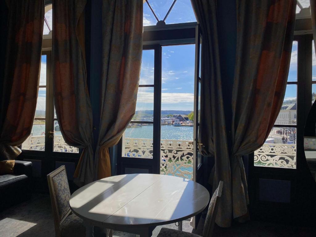 Una mesa en una habitación con vistas al agua en Best Western Le Cheval Blanc -Vue sur le port-plein centre ville, en Honfleur