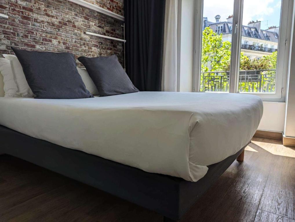 a large bed in a bedroom with a brick wall at Best Western Hotel Le Montparnasse in Paris