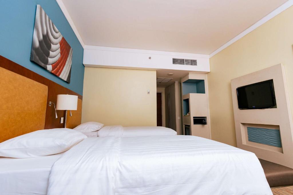 Schlafzimmer mit einem weißen Bett und einem Flachbild-TV in der Unterkunft Park Inn by Radisson, Kigali in Kigali