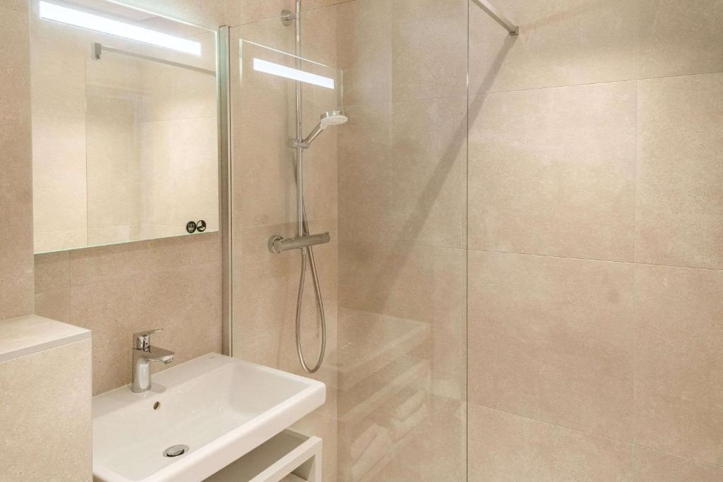 a bathroom with a shower with a sink and a glass shower door at Brit Hotel Nantes La Beaujoire Parc Expo in Nantes