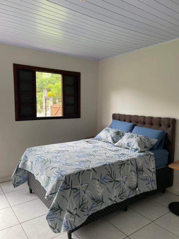 een slaapkamer met een bed met een blauw dekbed en een raam bij Casa de campo aconchegante in Córrego do Bom Jesus
