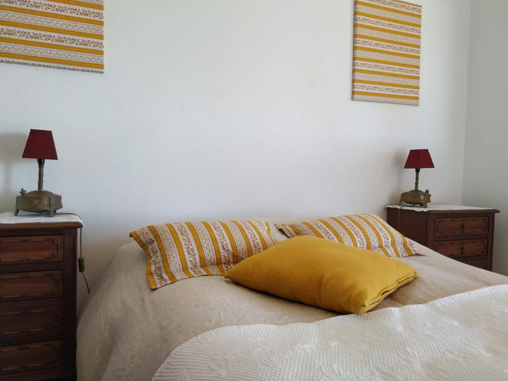 Una cama con una almohada amarilla encima. en Monte da Bela Vista, Colos, en Colos