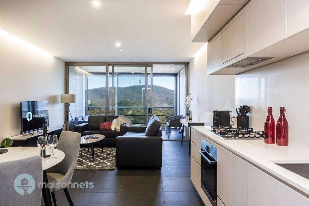 eine Küche und ein Wohnzimmer mit einem Sofa und einem Tisch in der Unterkunft 1 Bedroom Apt With Parking Walk to ANU in Canberra
