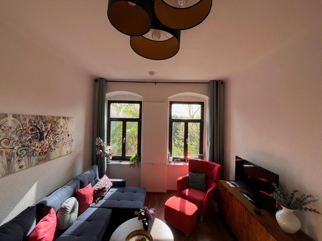 a living room with a blue couch and red chairs at Gäste-Appartements Morgensonne & Sonnenschein in Dresden