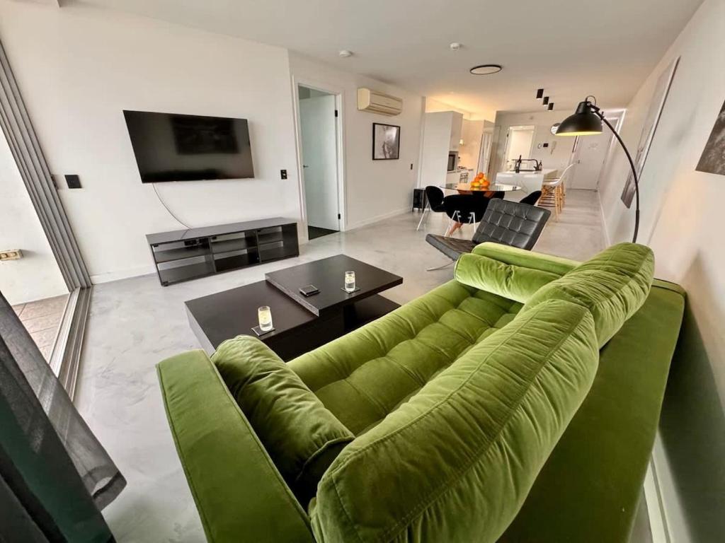 布里斯本的住宿－Spacious River view 3 Bdrm Apt with 2 Car spaces，客厅配有绿色沙发和桌子